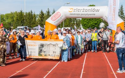Duża grupa uśmiechniętych seniorek przy dmuchanej mecie ustawionej na bieżni
