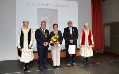 Para małżeńska wyrózniona medalem na zdjęciu z burmistrzem i dwiema dziewczynami w ludowych strojach