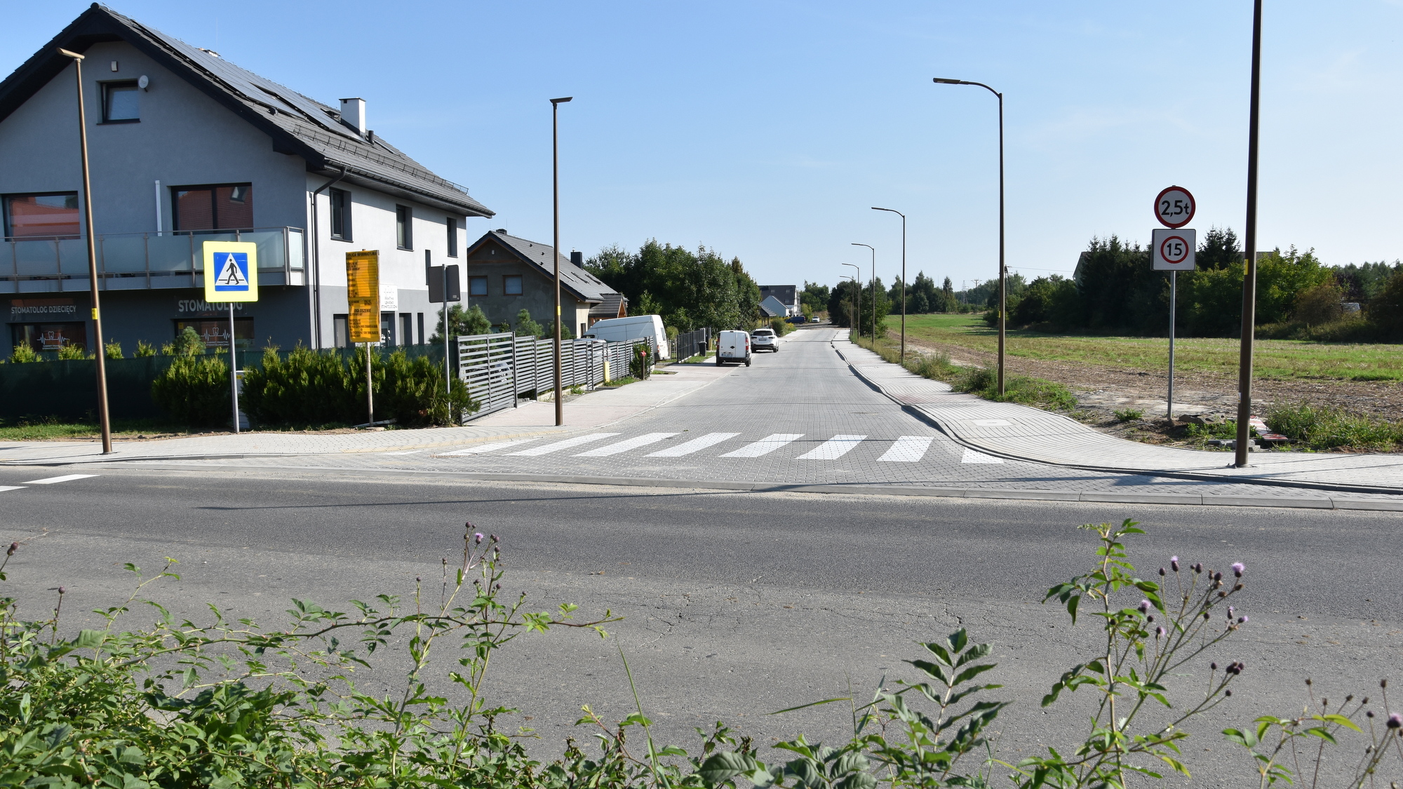 Widok na droge z kostki betonowej, obok budynki jednorodzinne