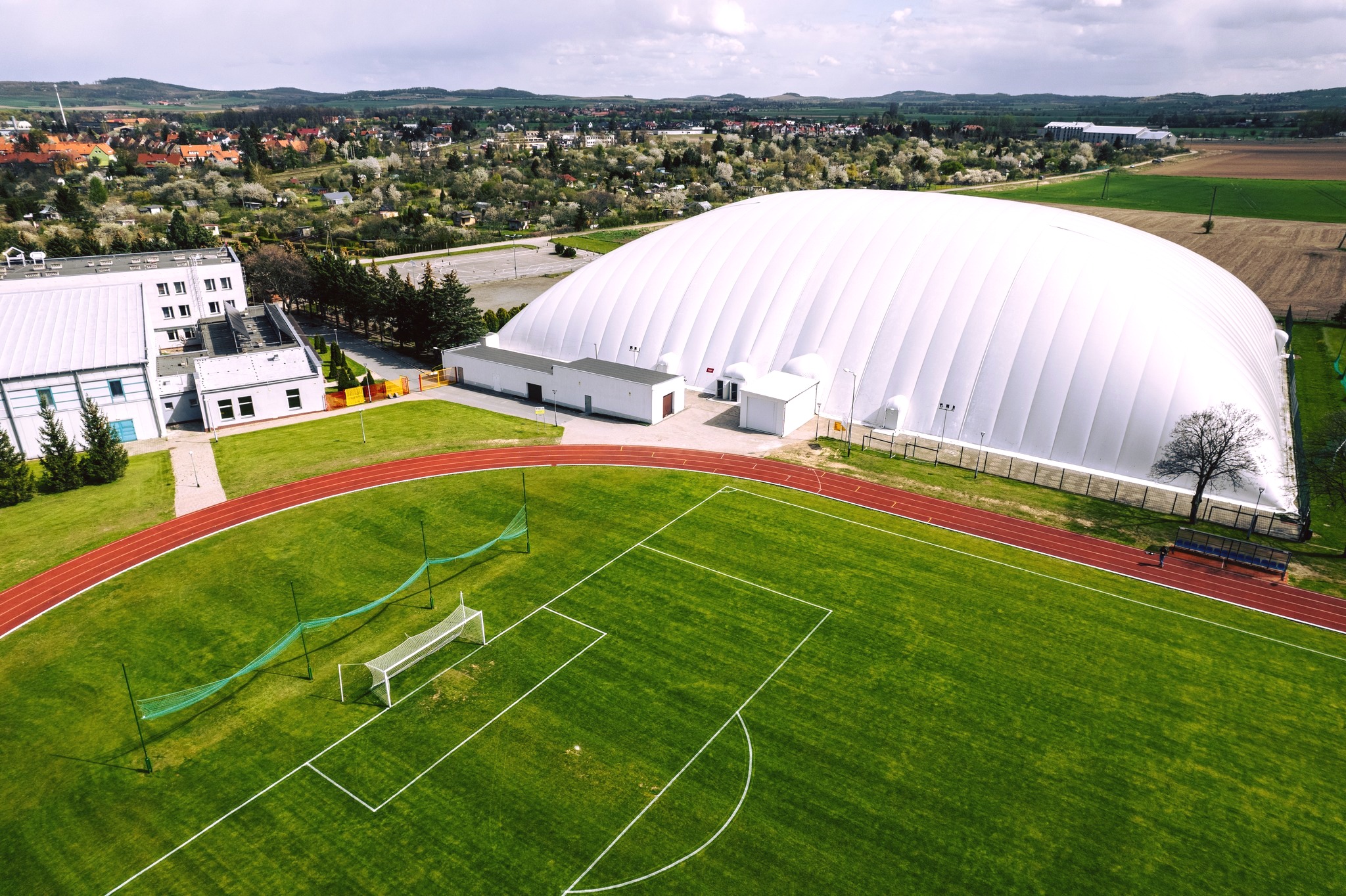 Boisko piłkarskie i biała hala sportowa wyglądająca jak balon