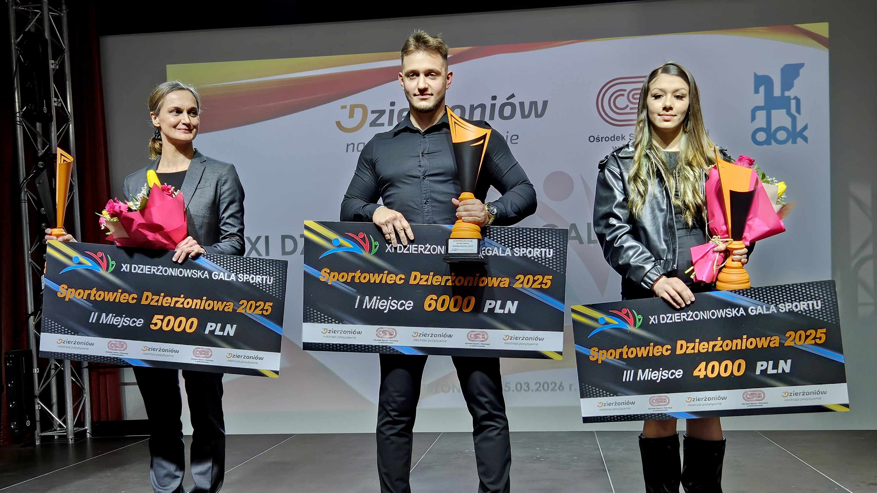 Laureaci trzech pierwszych zdjęć na scenie z pucharami i symbolicznymi czekami