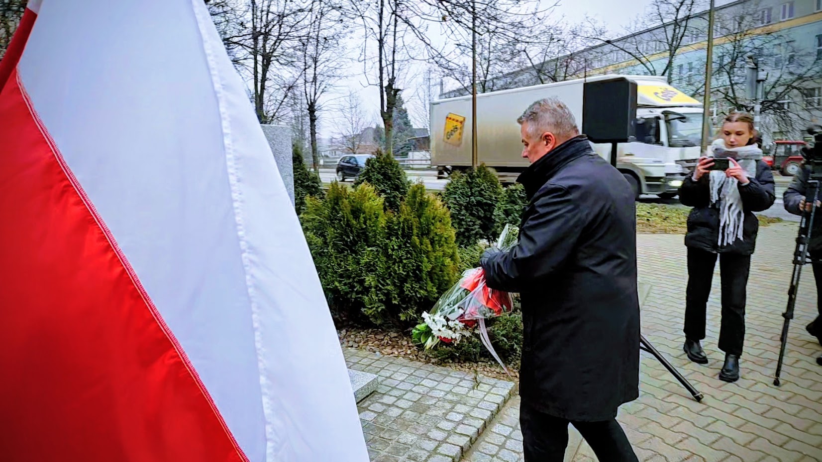 burmistrz Dariusz Kucharski składa wiązankę kwiatów pod obeliskiem mjra Woźniaka