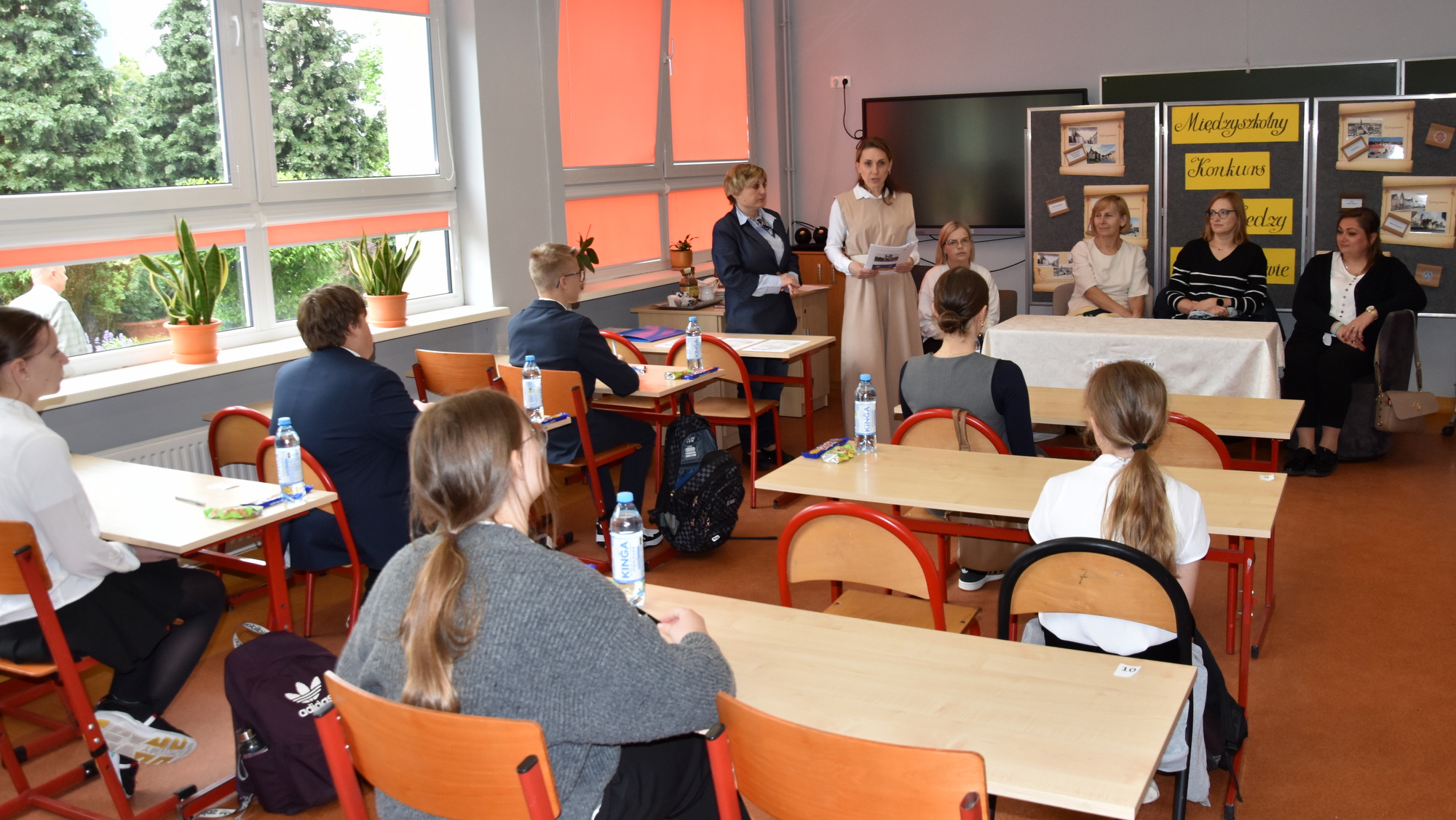 Uczniowie siedzący pojedyńczo w ławkach w szkolnej klasie