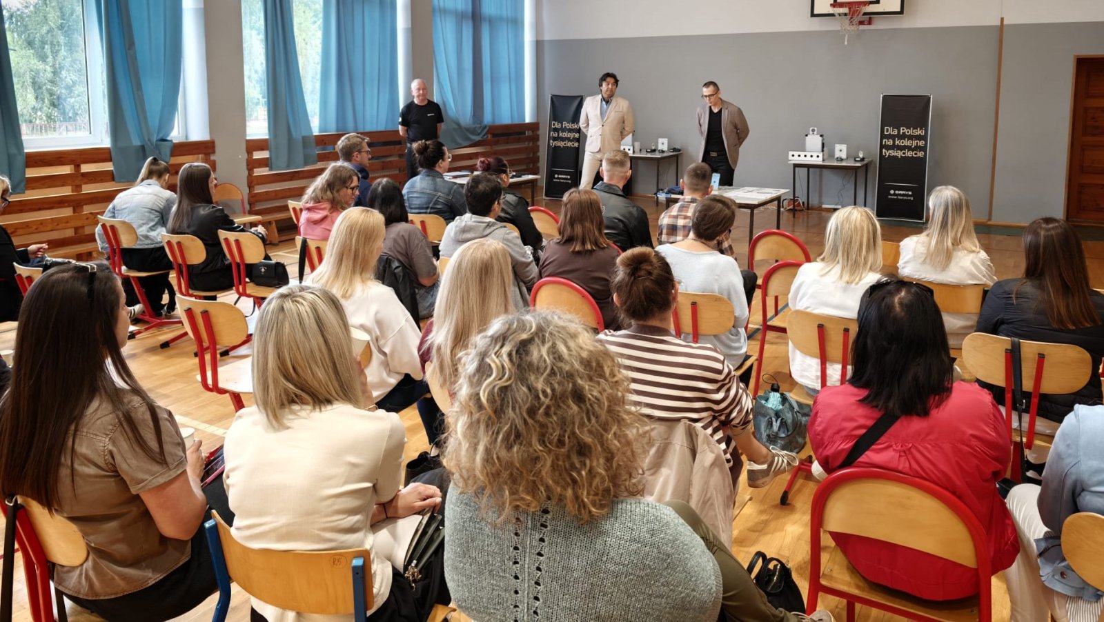 Kilkanaście osób siedzących na krzesłach podczas szkolenia w dużej sali