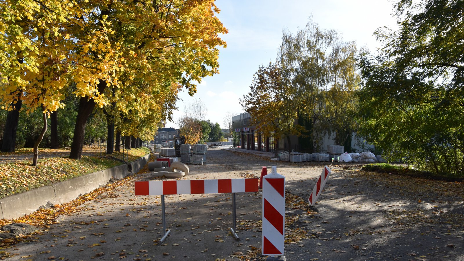 Droga w przebudowie, zagodzona biło-czerownymi znakami, dookoła zieleń 