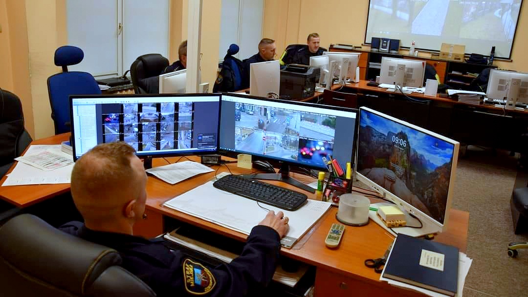 Strażnik miejski obserwujący ekrany komputerów pokazujących obraz z kamer monitoringu