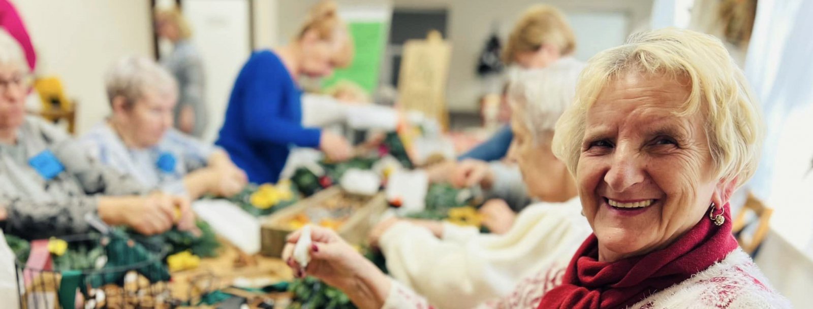 Usmiechnięta seniorka siedząca przy stole 