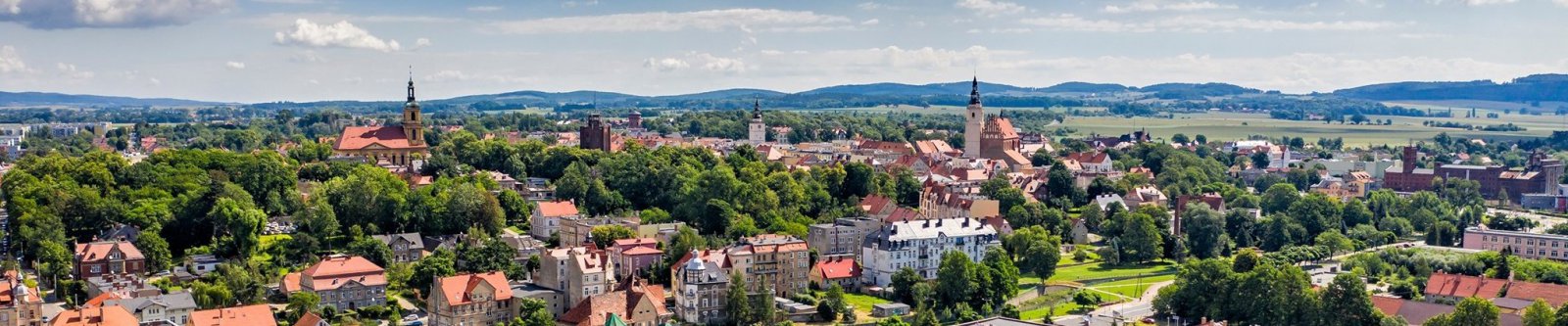 Panorama miasta z lotu ptaka, w tle zadrzewione góry