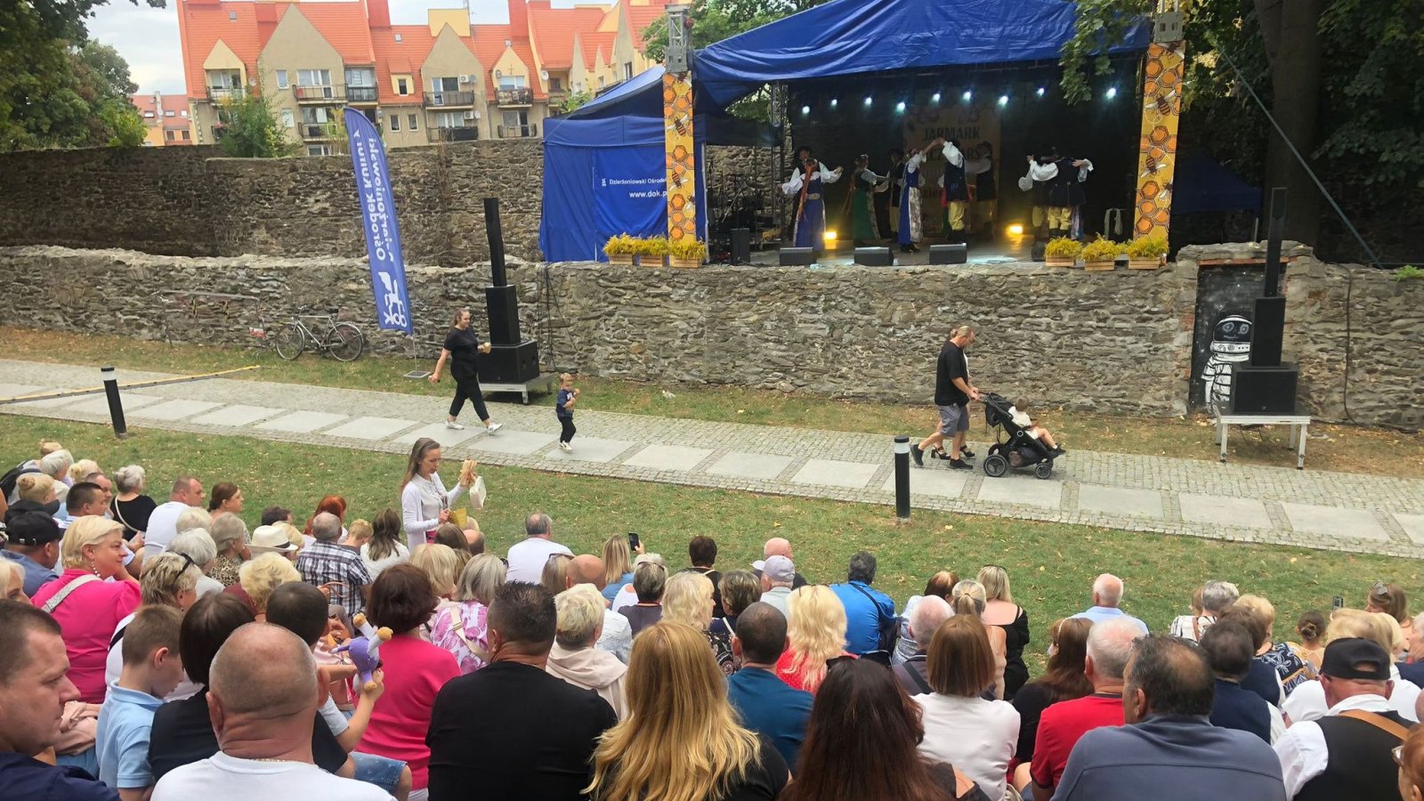 Scena przy kamiennych murach, przed sceną cchodnik i widownia