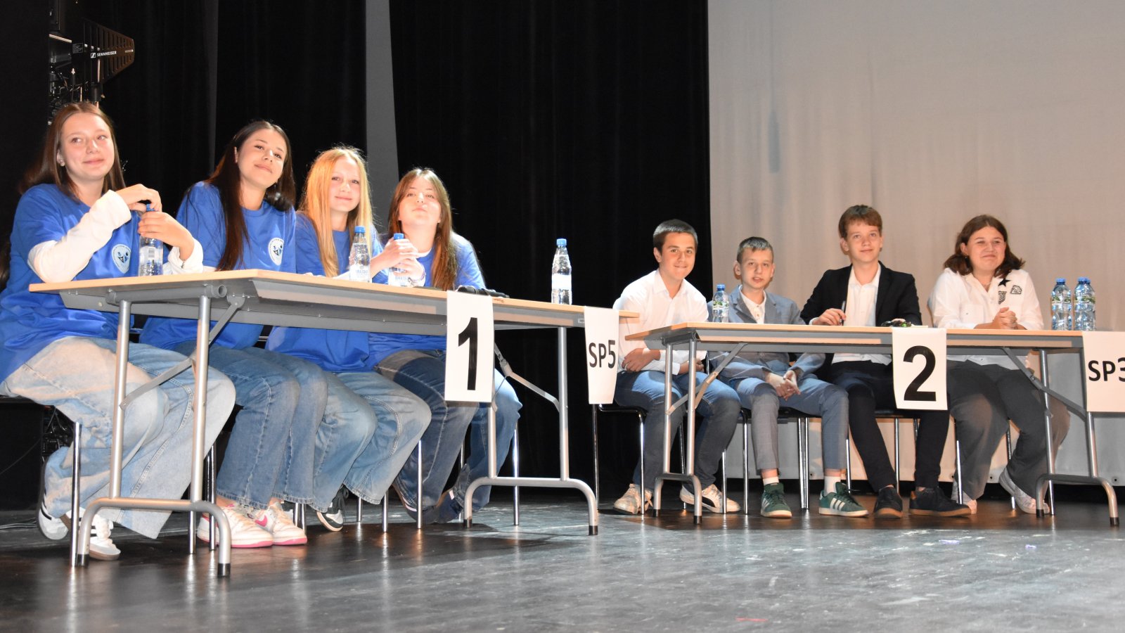 Dwa czteroosobowe zespoły uczniów przy dwóch stolikach