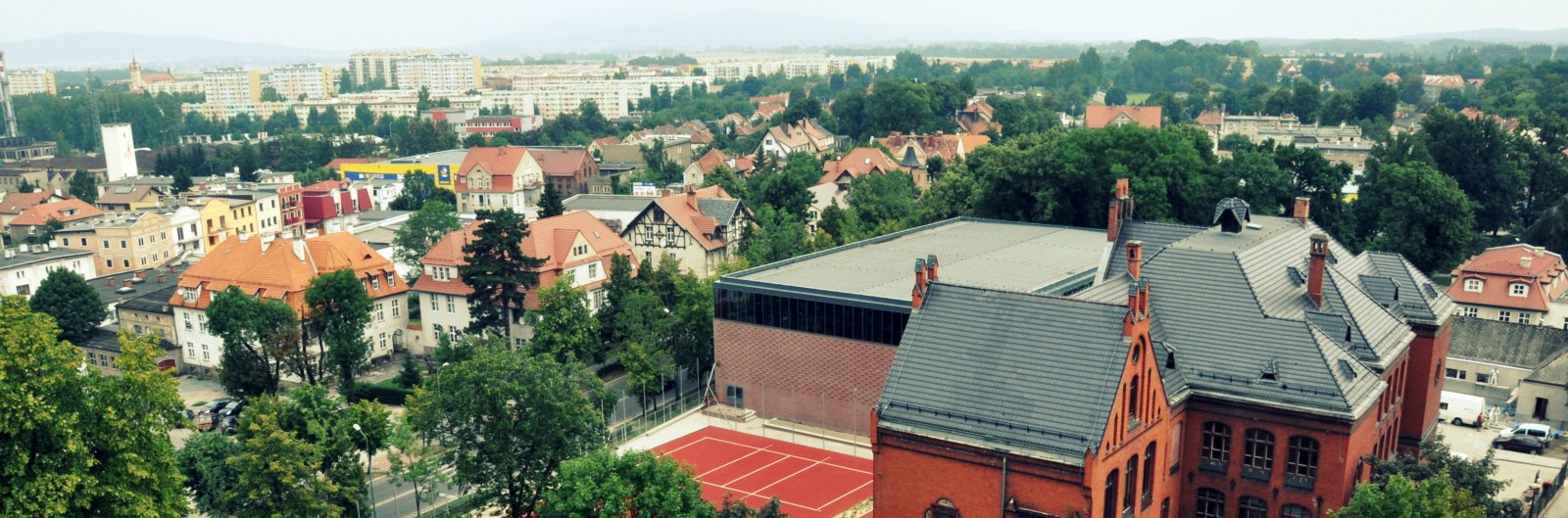 Fragment miasta z lotu ptaka, na pierwszym planie duża kamienica z czerwonej cegły