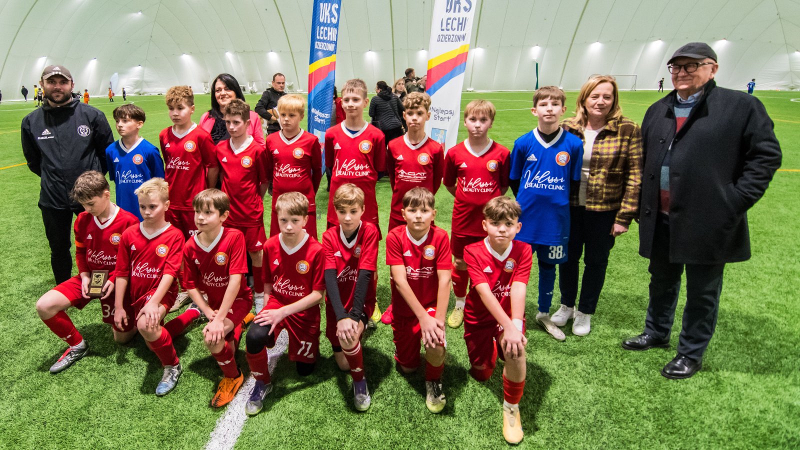 Zdjęcie druzyny piłkarskiej w czerwonych strojach, obok trener