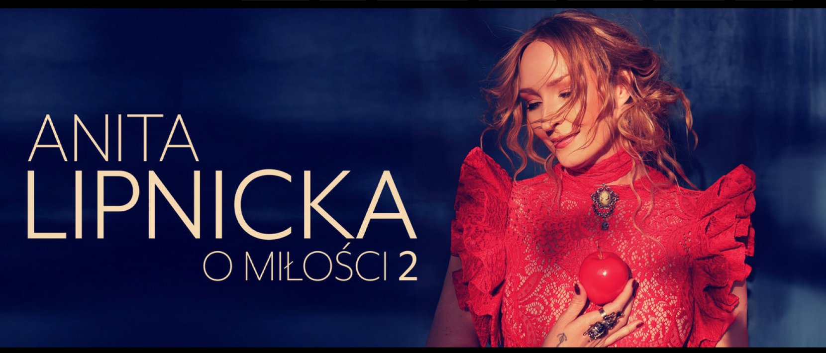Anita Lipnicka w czerwonej sukience i z jabłkiem w dłoni