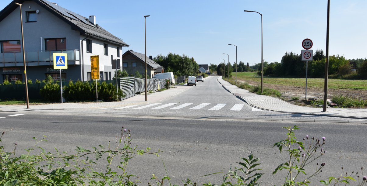 Widok na droge z kostki betonowej, obok budynki jednorodzinne