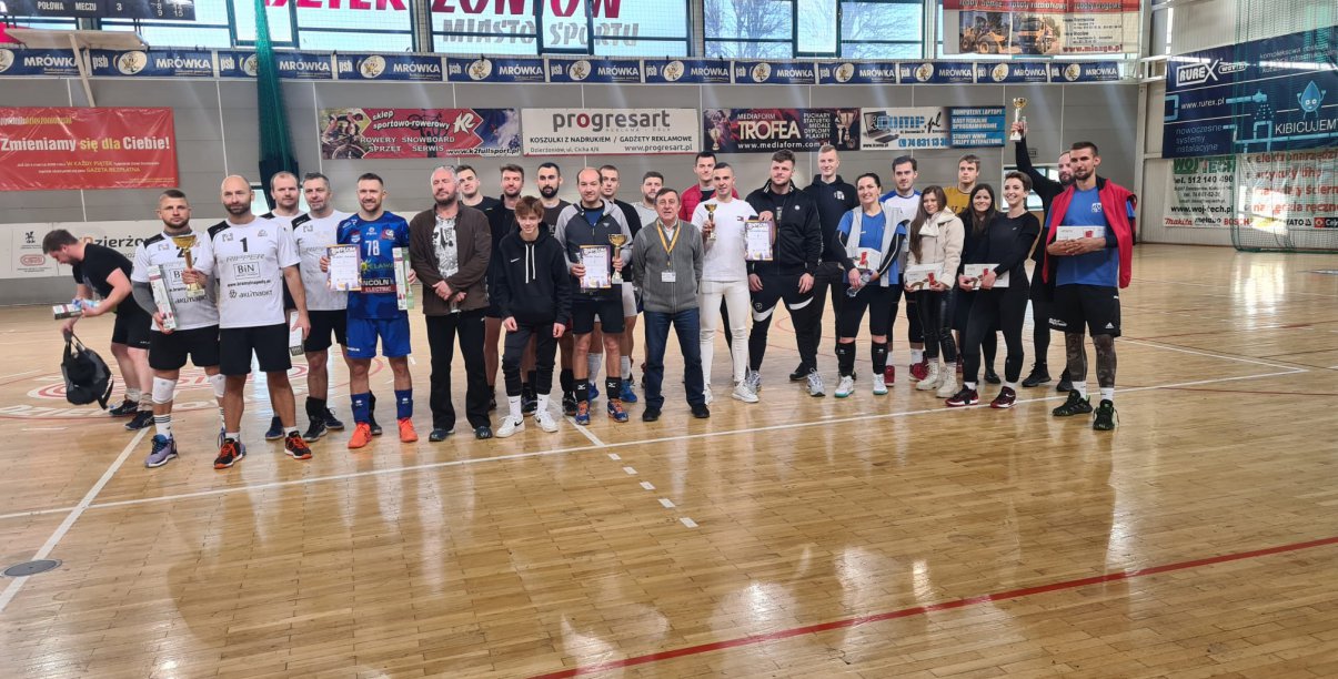 zawodnicy z pucharami w hali sportowej