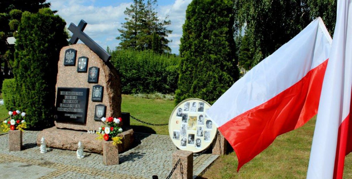 Kamienny obelisk na cmentarzu i flaga Polski