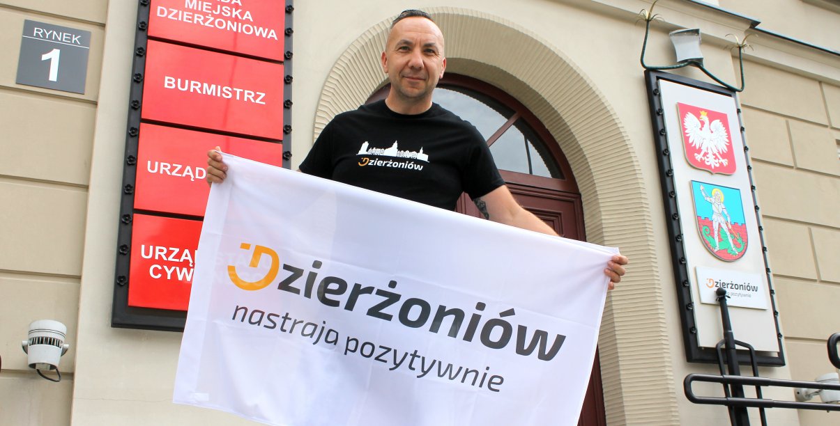 Mężczyzna przed wejściem do ratusza z banerem z napisem Dzierżoniów