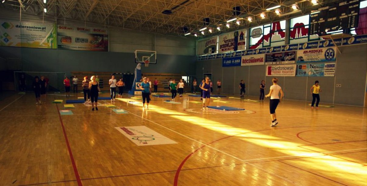 Hala sportowa, grupa pań ćwiczy na parkiecie