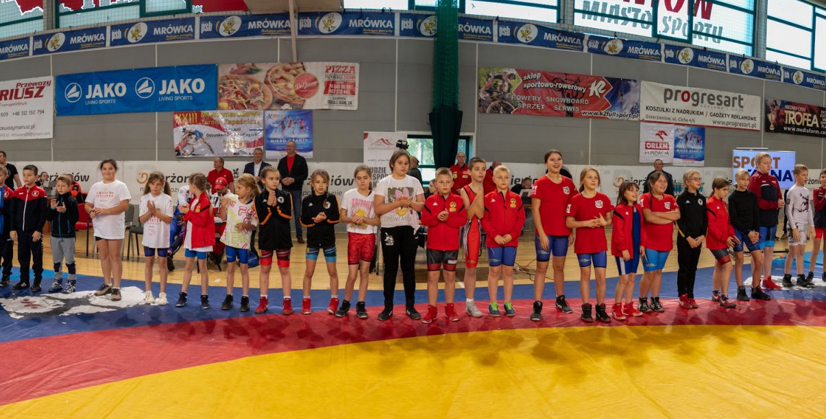 Grupowe zdjęcie kilkudziesięciu zapaśników w hali sportowej