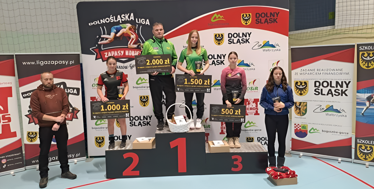 Zapaśniczki stojące na podium z symbolicznymi czekami