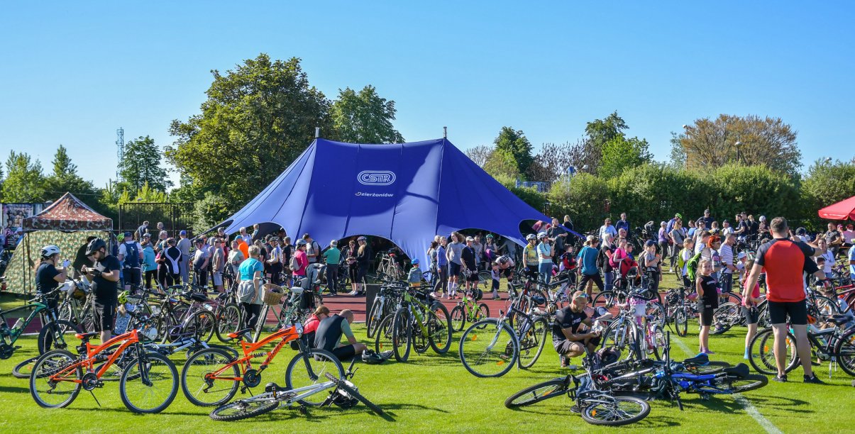Kilkudzisięciu rowerzystów przy dużym niebieskim namiocie
