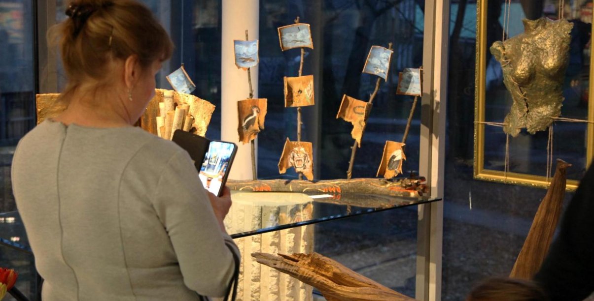 Kobieta z telefonem z dłoni robiąca zdjęcie artystycznej rzeźby