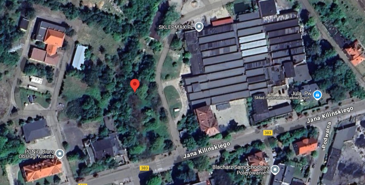 Fragment miasta z budynkami i dużą halą przmyłową z góry. Czerwonym punktem zaznaczono teren objęty przetargiem