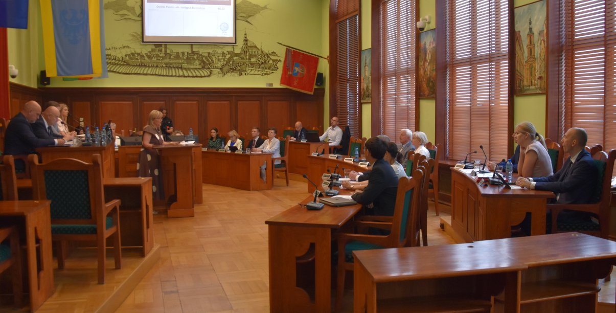 Grupa radnych na sali rycerskiej ratusza podczas sesji rady miejskiej