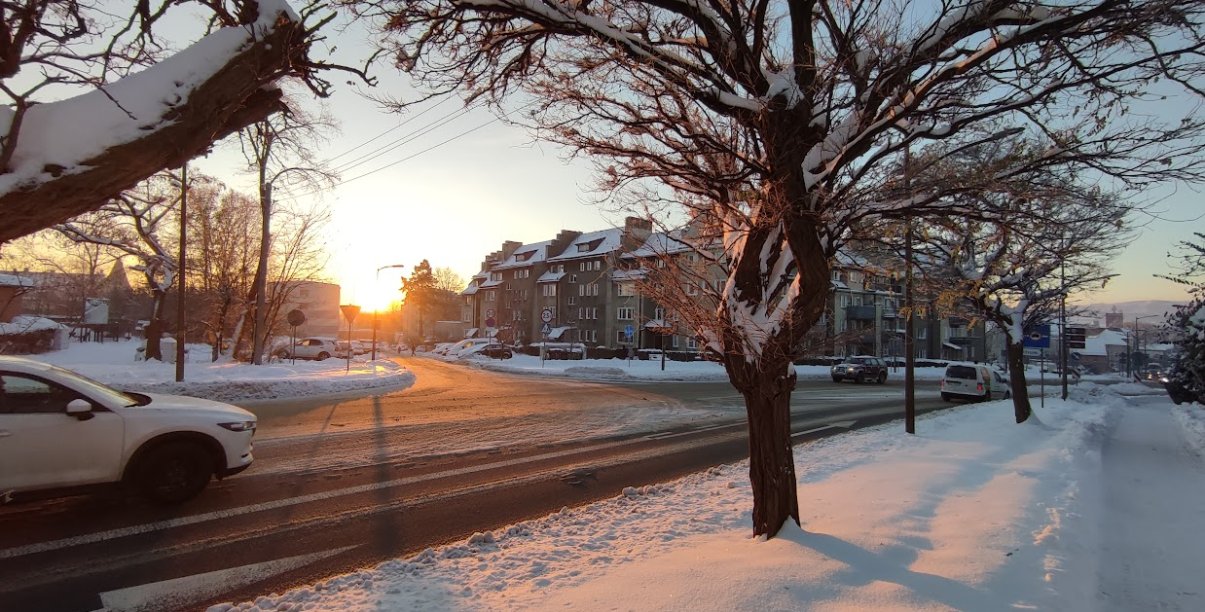 zimowa aura na ul. batalionów chłopskich, przejeżdzający biały samochód, ośnie zone chodniki i drzewa