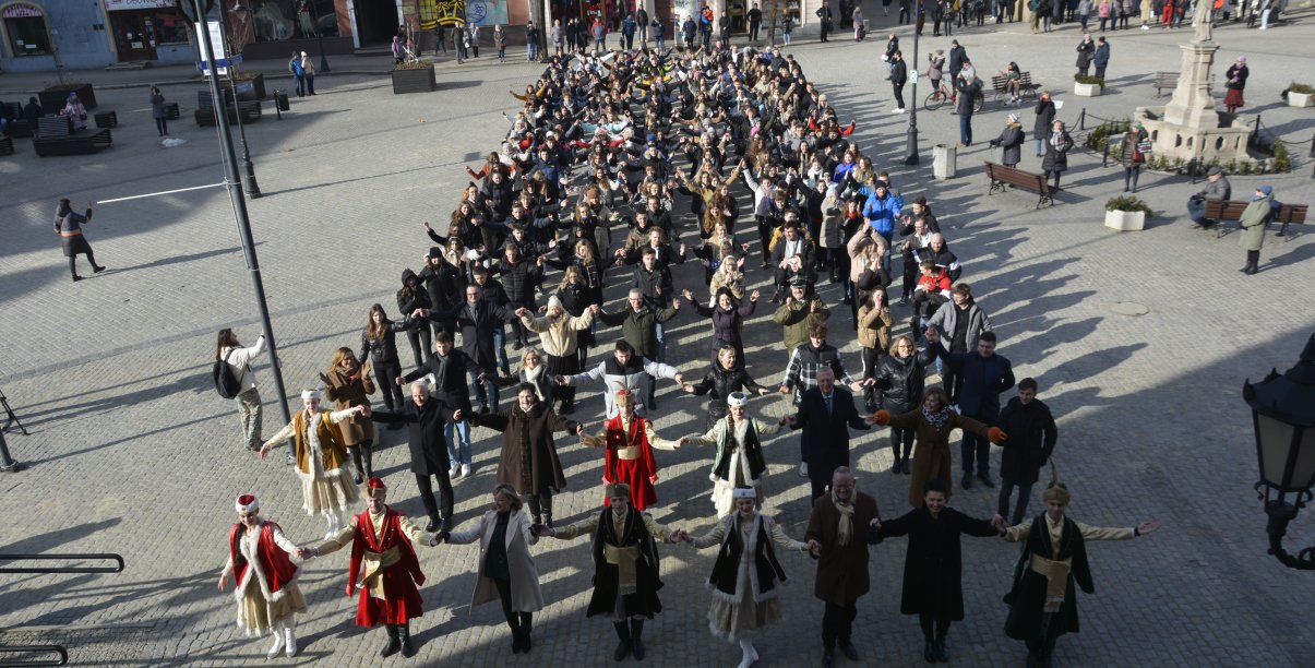 Duża grupa tanczących poloneza osób na płycie rynku