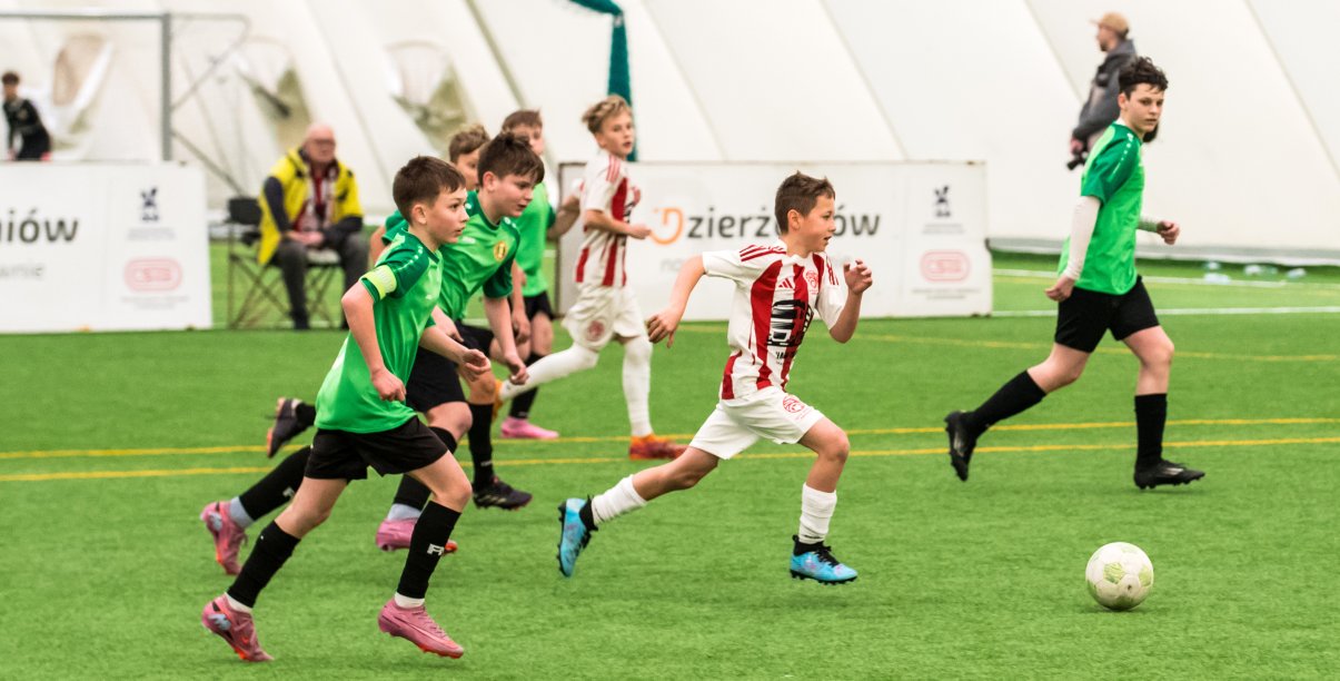 Młodzi piłkarze podczas meczu, obok sędzia