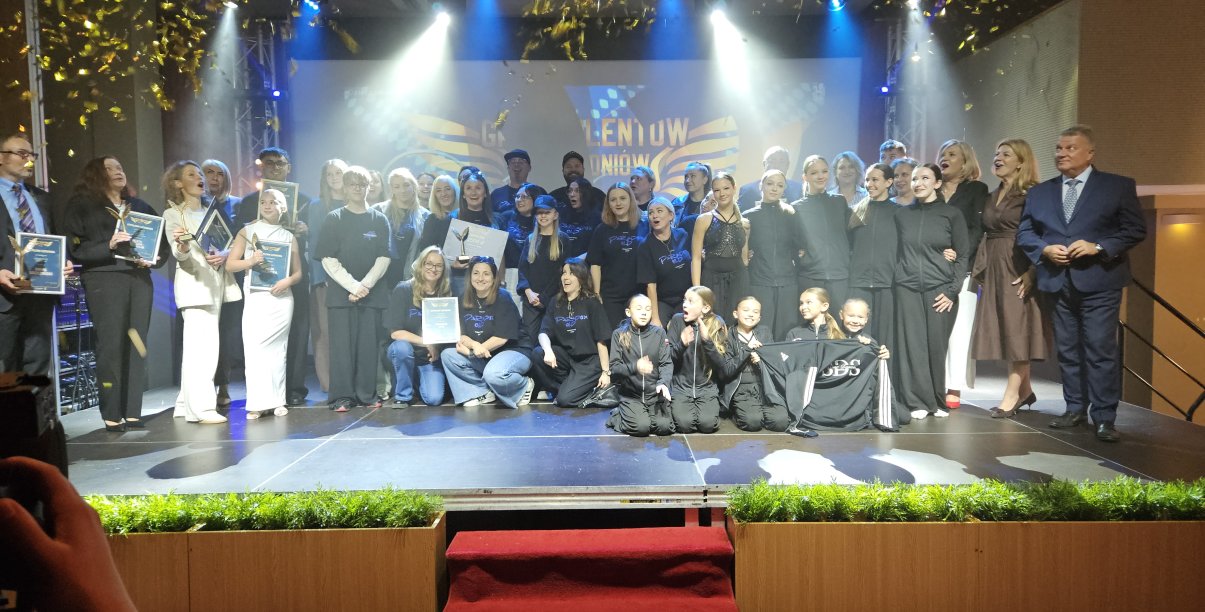 Wszyscy laureaci na wspólnym zdjęciu na scenie patrzą na lecące z góry konfetti