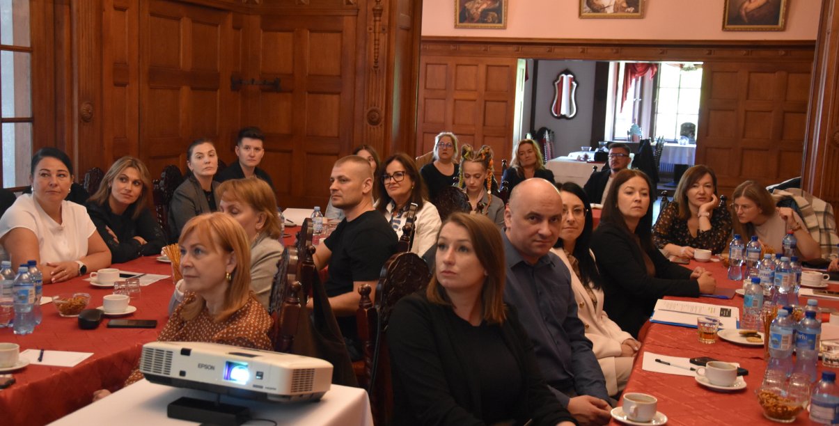 Duża grupa uczestników szkolenia siedząca przy stołach