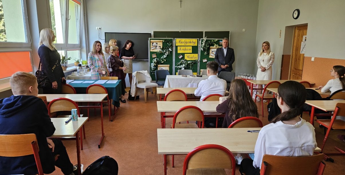 w klasie szkolenej dzieci w ławkach, widok na tablicę, przy któej pzremawia burmistrz Dzierżoniowa, obok nauczycielki