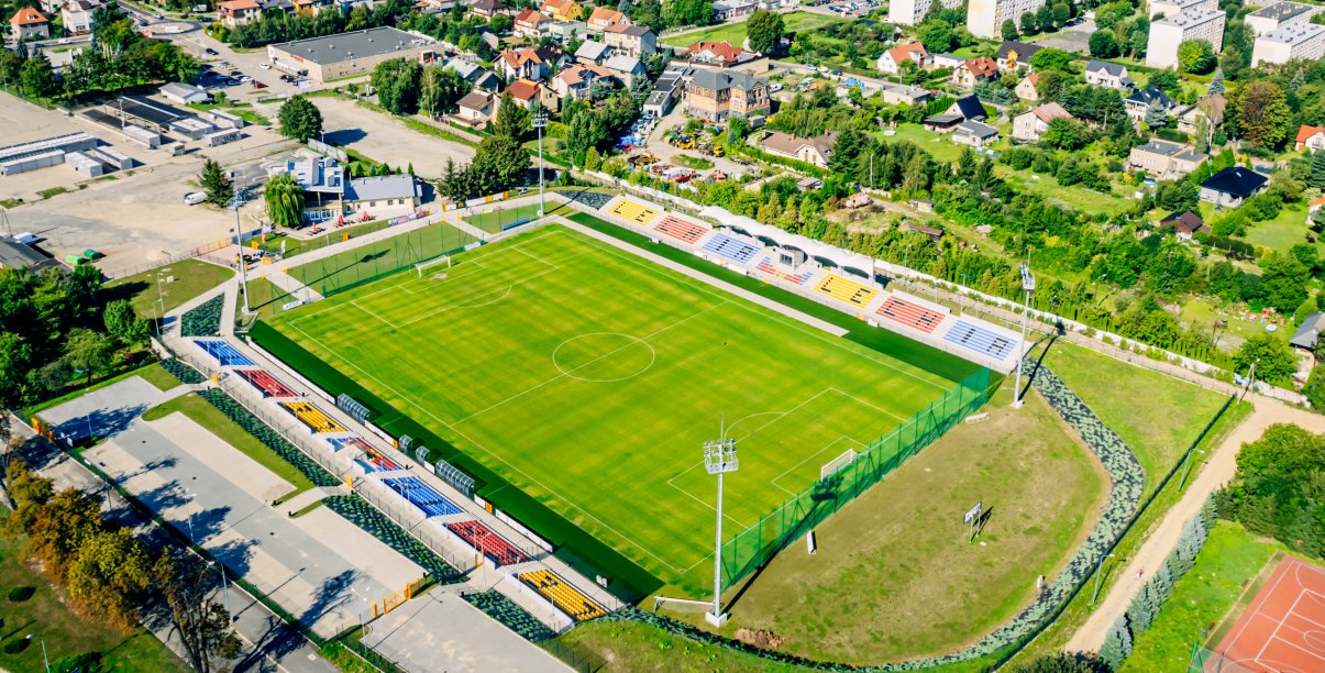 Stadion z góry, obok duży parking i plac targowy
