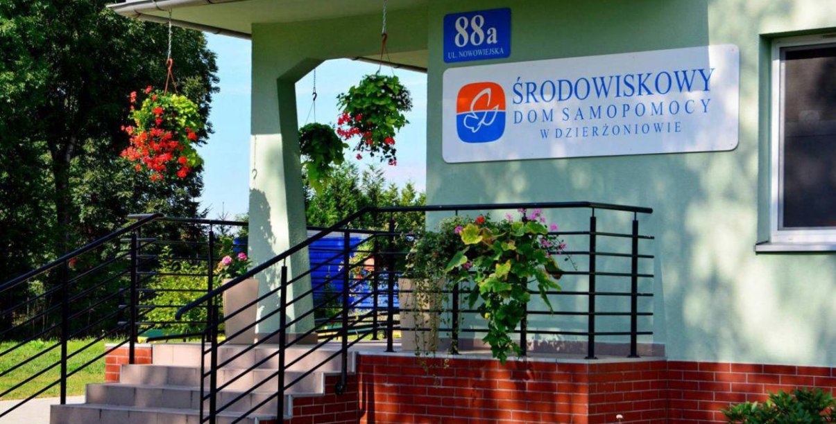 Wejście po schodach prowadzące tarasem do budynku, na ścianie napis Środowiskowy Dom Samopomocy