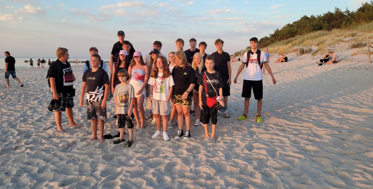 Grupa młodzieży na plaży, po prawej wydmy
