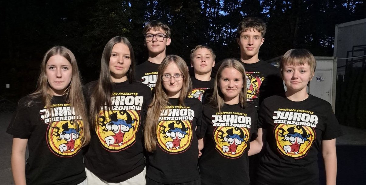 Grupowe zdjęcie zawodniczek i zawodników w jednakowych czarnych koszulkach z logotypem klubu