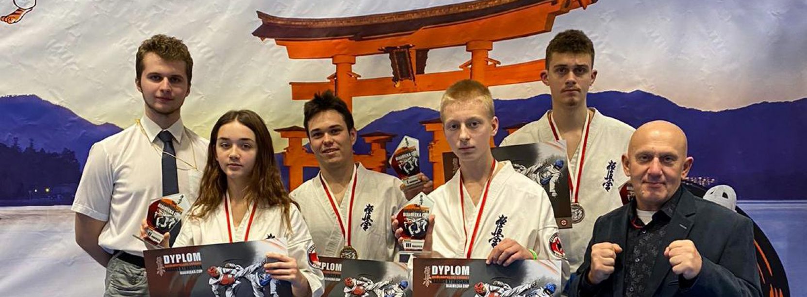 Grupowe zdjęcie zawodników strojach karate i z dyplomami