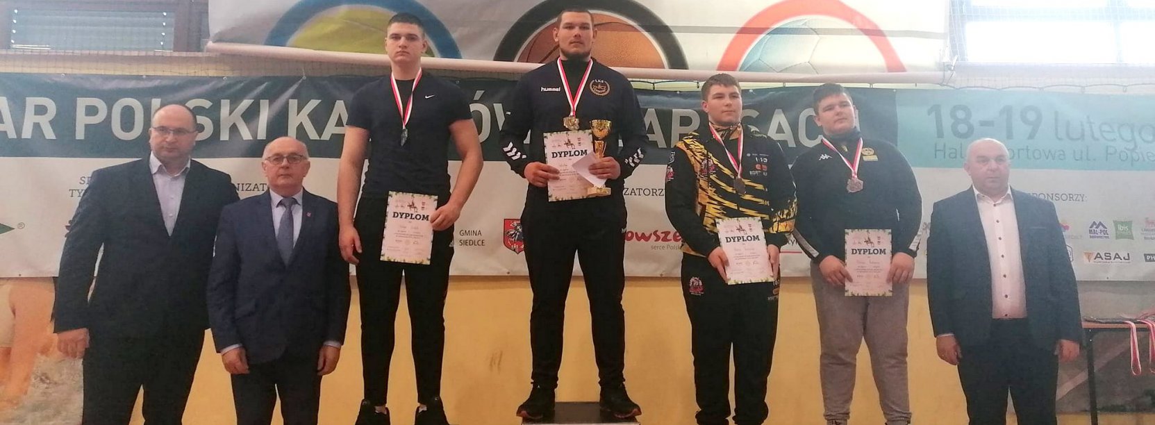 Zawodnicy z dyplomami na wspólnym zdjęciu na podium , obok trenerzy