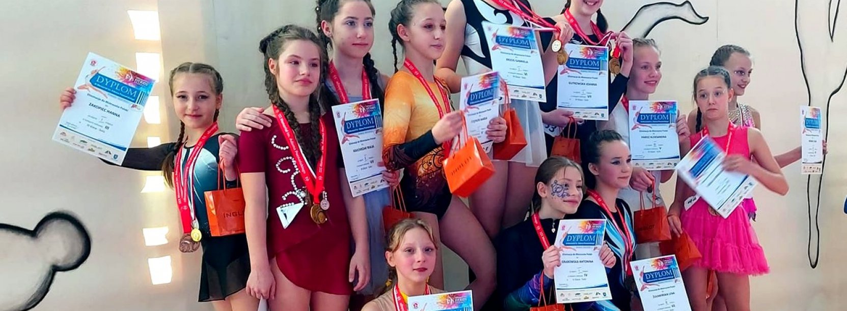 Kilkanaście młodych akrobate na wspólnym zdjęciu, każda trzyma dyplom