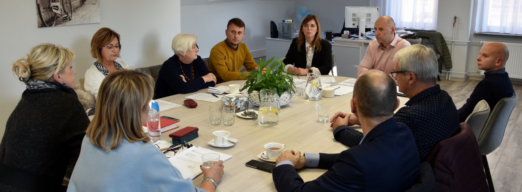 Grupa osób siedząca przy stole w jasnym pomieszczenu