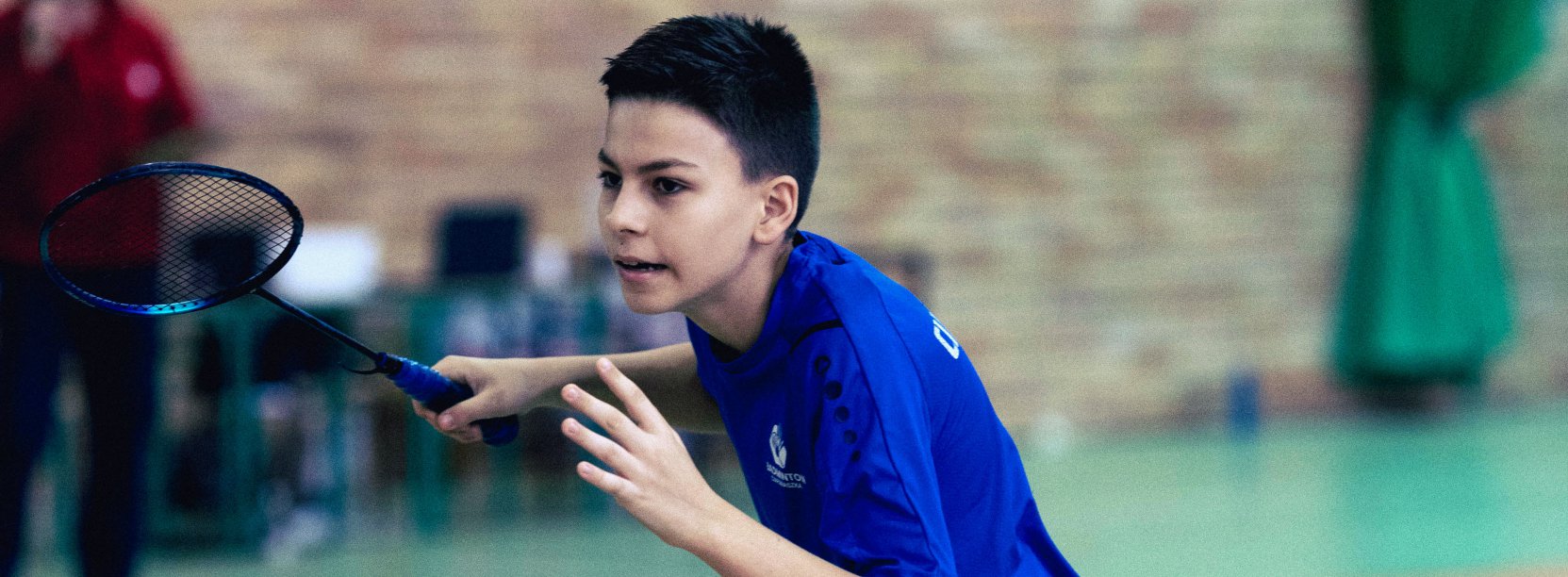 Chłopiec w ciemnoniebieskej koszulce z rakieta do badmintona