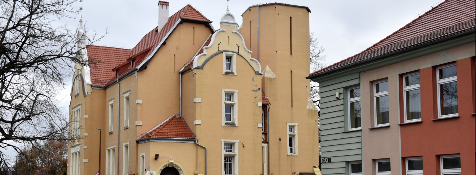 Zółta kamienica z nowym dachem z czerwonej dachówki