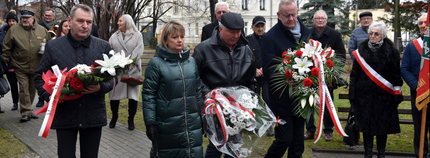 Grupa osób składająca wieńce przed pomnikiem
