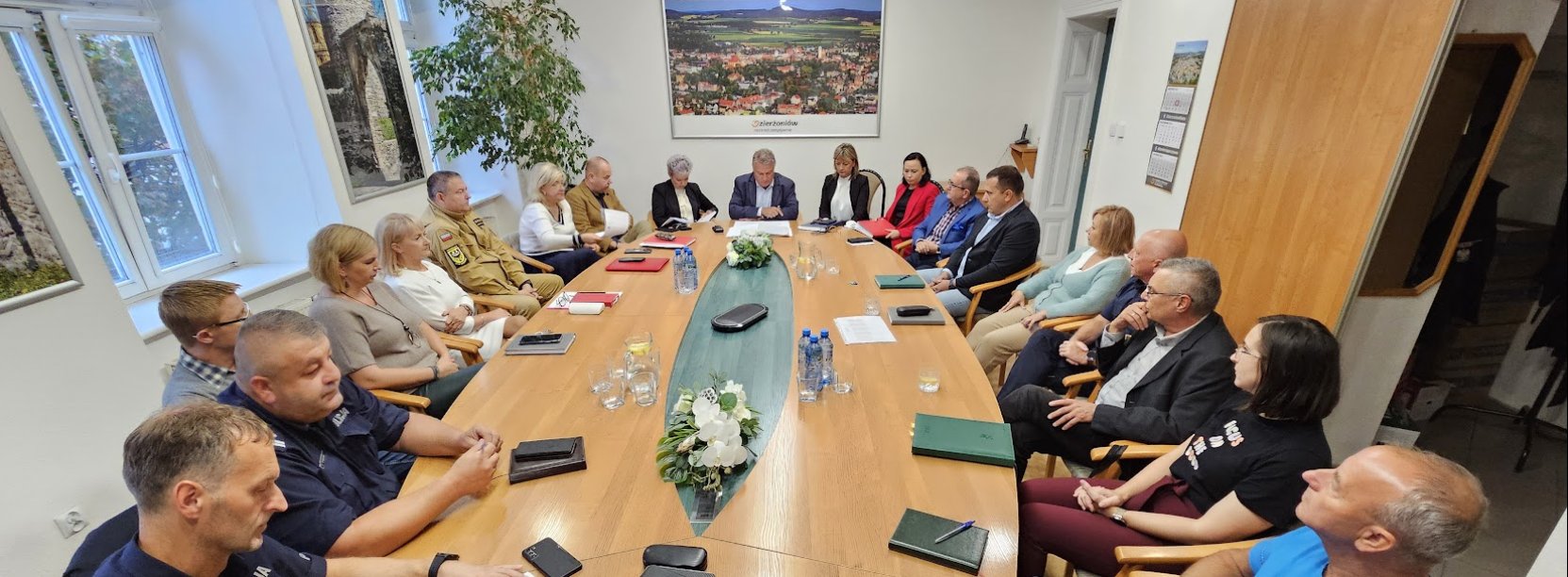 duża grupa ludzi siedząca przy owalnym stole, n a szczycie burmistrz Dzierzoniowa Dariusz Kucharski