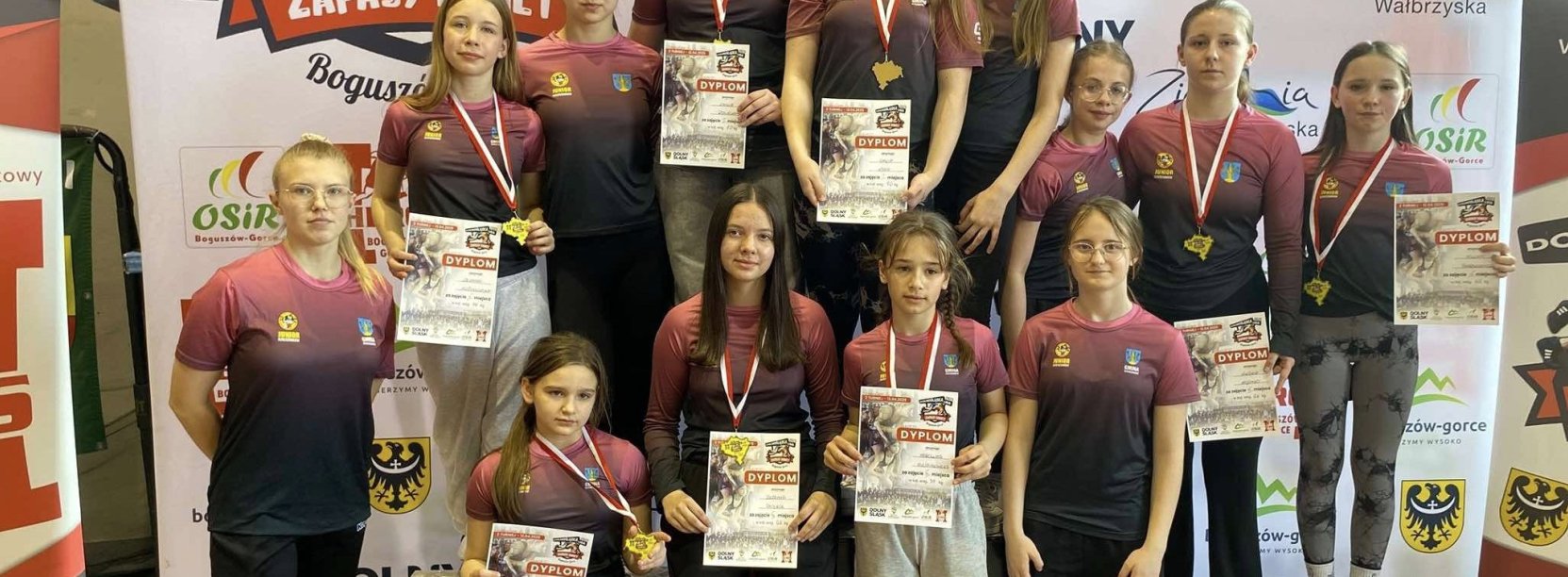 Grupowe zdjęcie dzierżoniowskich zapaśniczek w jednolitych strojach, z dyplomami w dłoniach
