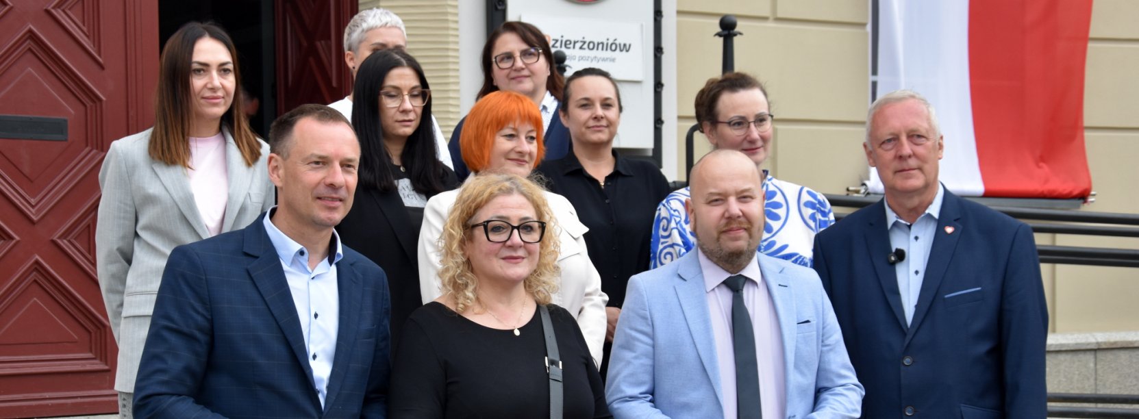 Grupa osób przed wejściem do ratusza na wspólnym zdjęciu