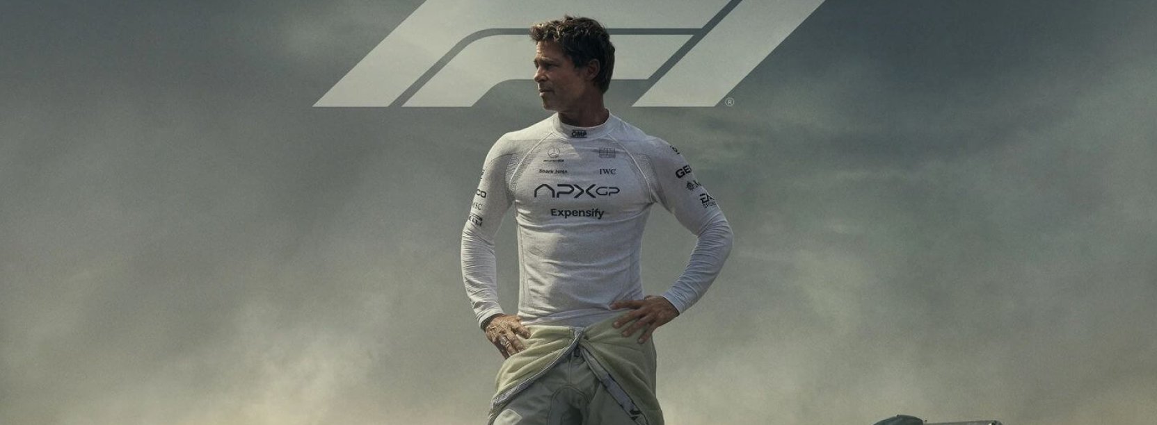 Mężczyzna w białej koszulce, za nim bolid formuły F1