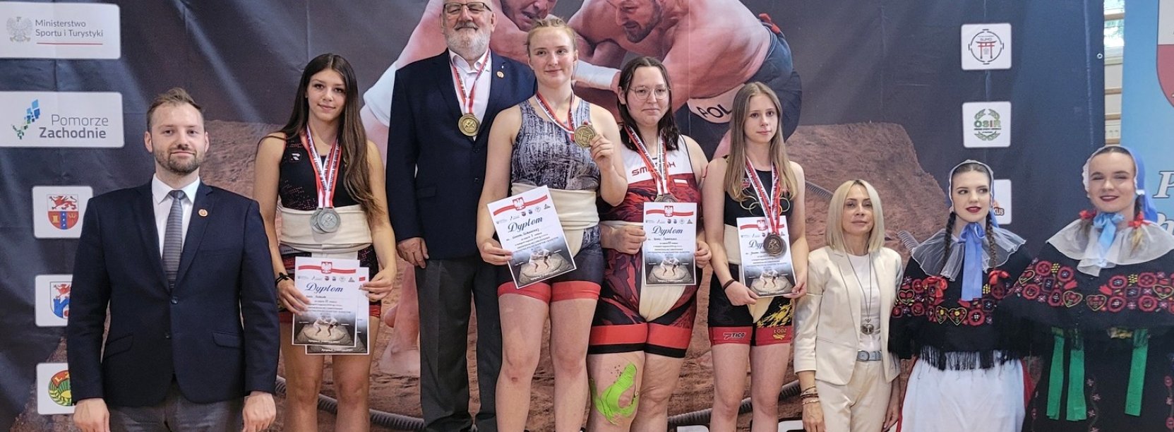 Zawodniczki na podium, po bokach trenerzy